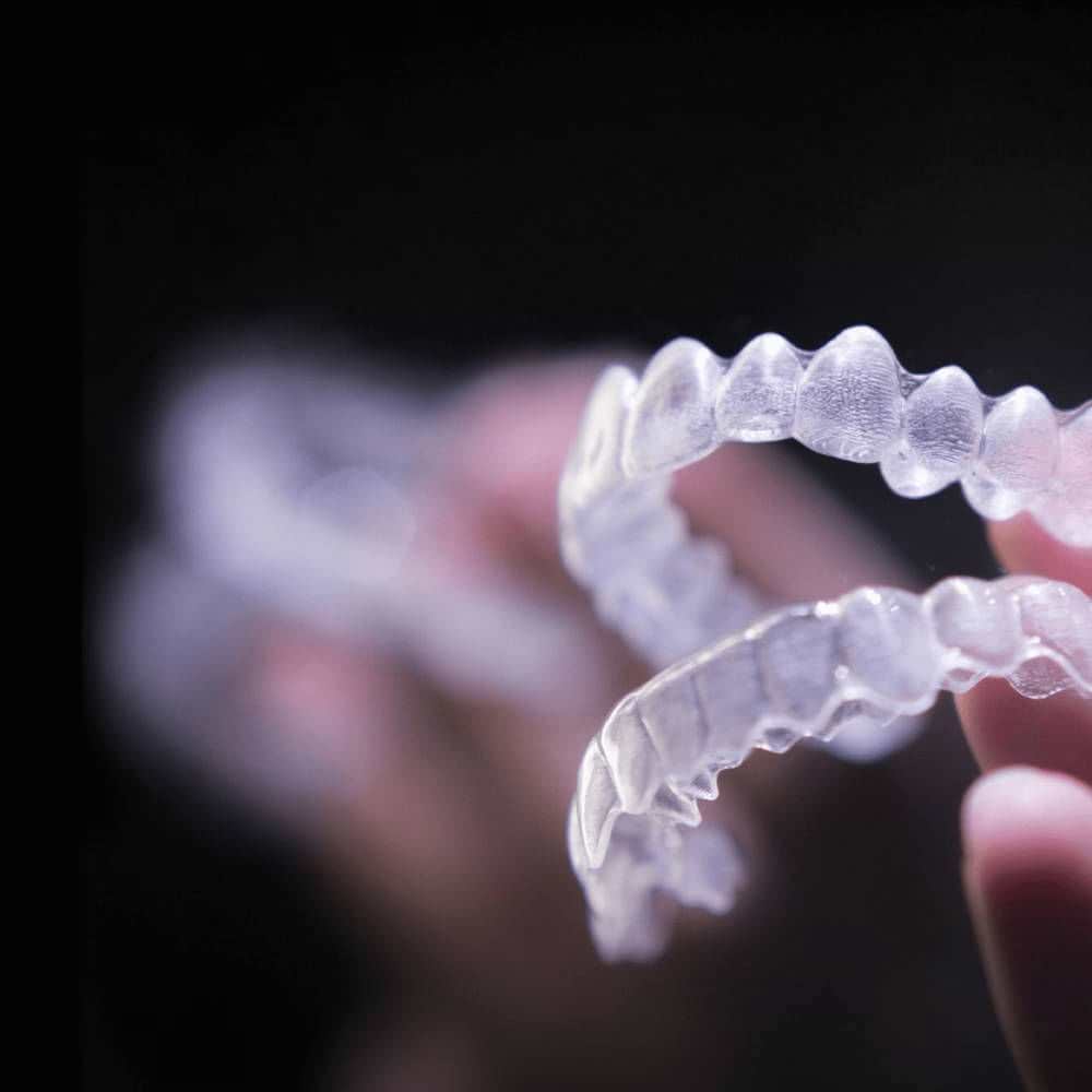 A hand holding an SureSmile clear aligner tray